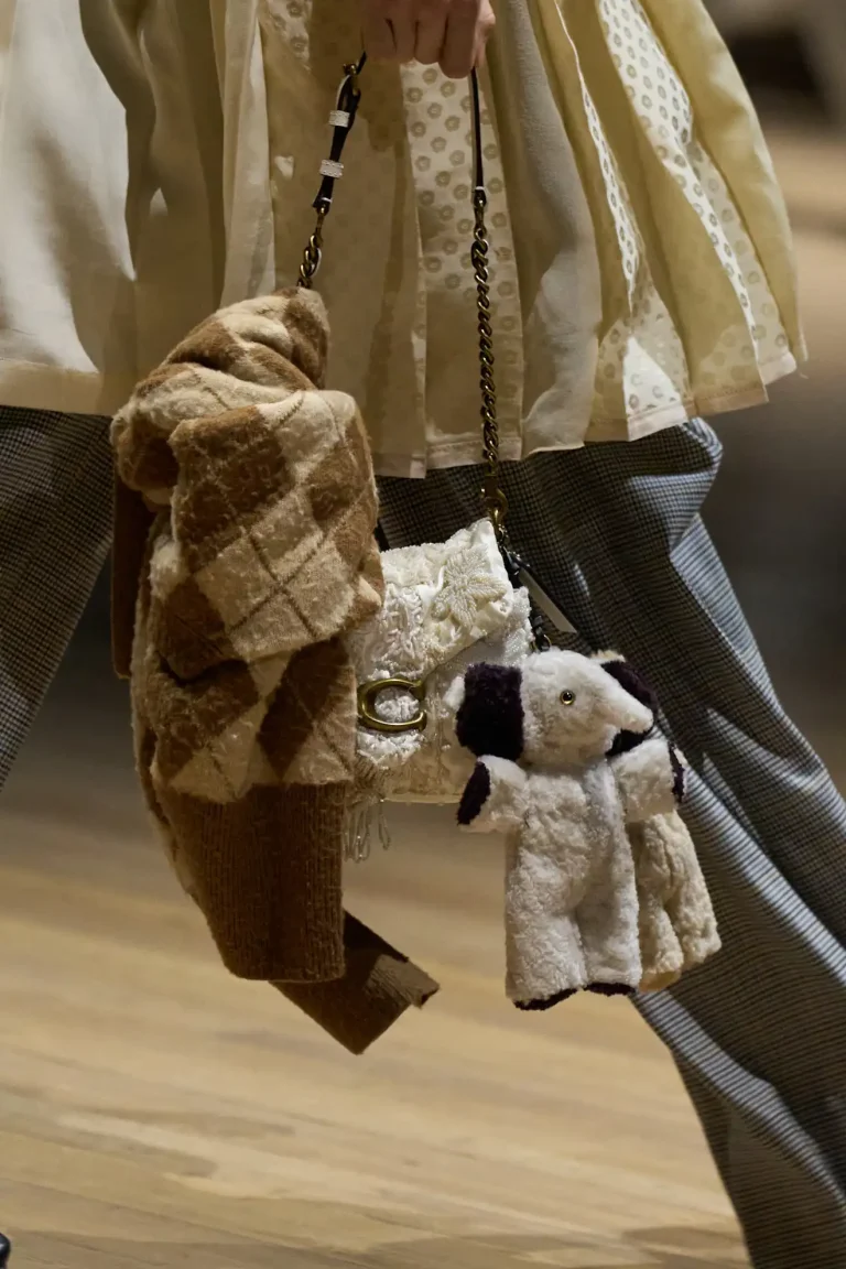 White Coach bag with plush animal and knit accessories attached